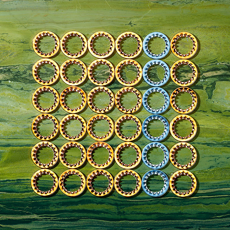 Eine Sammlung von runden, goldenen und blauen Ringen auf einem strukturierten grünen Hintergrund. Die Ringe sind in einer ordentlichen 7x7-Anordnung angeordnet, wobei die goldenen Ringe in der Mehrheit sind und die blauen Ringe in der Mitte hervorgehoben werden.